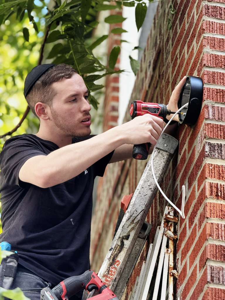 Sruly Reznik personally installing a camera housing on a brick wall
